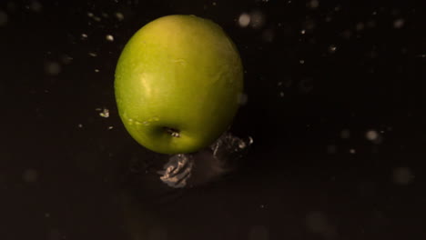 Grüner-Apfel-Fällt-Auf-Nasse-Schwarze-Oberfläche