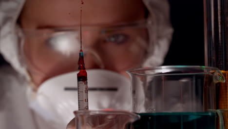 Scientist-spraying-syringe-of-red-chemical