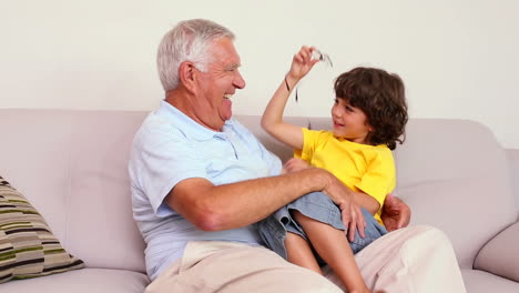 Senior-man-sitting-on-couch-with-his-grandson-