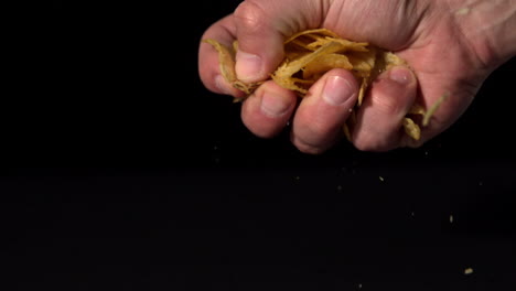 Hands-crushing-potato-chips-on-black-background