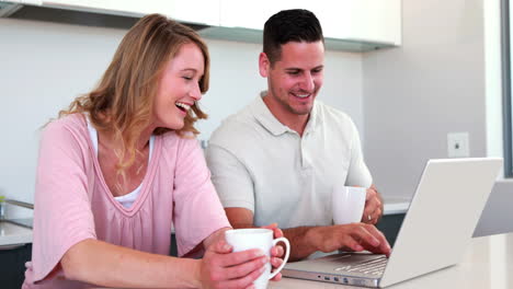Happy-couple-using-the-laptop-together-and-having-coffee