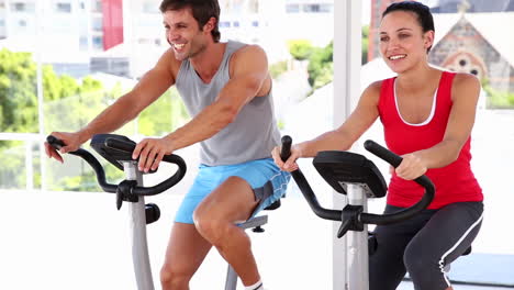 Fit-couple-working-out-on-exercise-bikes-