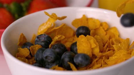 Arándanos-Vertiendo-En-Un-Tazón-De-Cereal-En-La-Mesa-Del-Desayuno