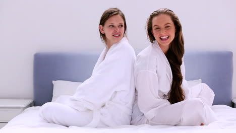 Girls-wearing-bathrobes-chatting-on-bed
