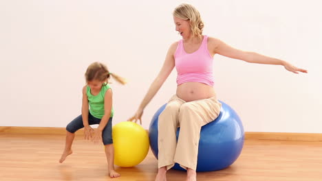 Blonde-Schwangere-Frau-Sitzt-Auf-Gymnastikball-Mit-Ihrem-Kleinen-Mädchen