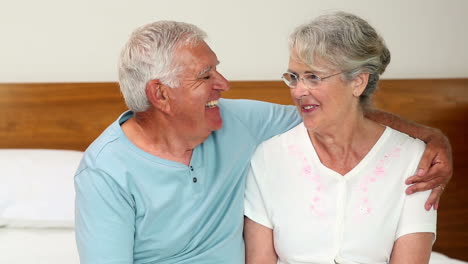 Senior-couple-sitting-on-bed-chatting