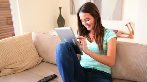 Pretty-brunette-relaxing-on-the-sofa-using-her-tablet-pc
