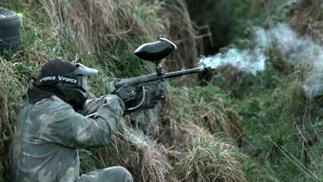 Hombre-Escondido-En-El-Suelo-Disparando-Una-Pistola-De-Paintball.