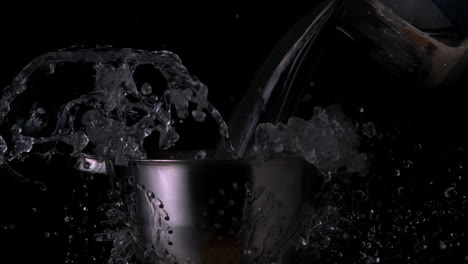 Water-pouring-over-colander-on-black-background