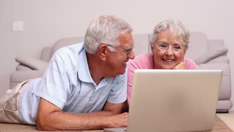 Älteres-Paar-Liegt-Auf-Dem-Boden-Mit-Laptop
