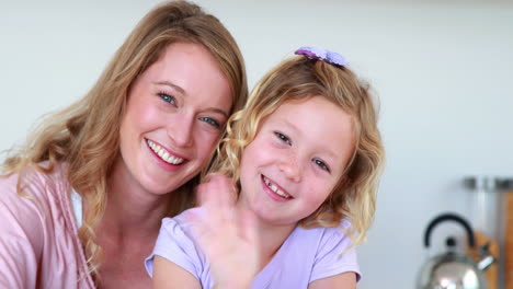 Pretty-mother-and-daughter-waving-and-smiling-at-camera