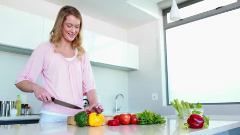 Smiling-woman-slicing-vegetables-on-a-chopping-board