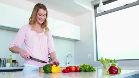 Mujer-Sonriente-Cortando-Verduras-En-Una-Tabla-De-Cortar