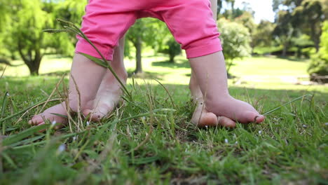 Baby-walking-on-mothers-feet-on-the-grass