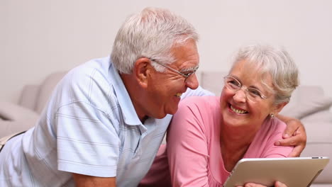 Senior-couple-lying-on-floor-using-tablet-pc