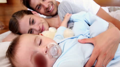 Happy-parents-lying-on-bed-with-baby-son