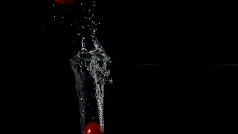 Cherry-tomato-falling-in-water-on-black-background