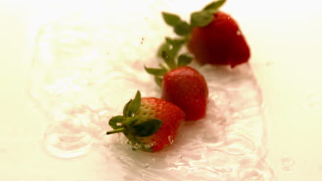 Strawberries-falling-on-white-wet-surface