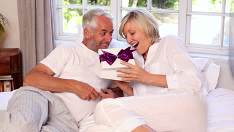 Man-surprising-his-partner-with-a-gift-on-bed