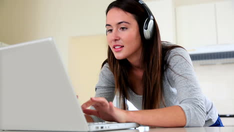 Pretty-brunette-using-laptop-and-listening-to-music