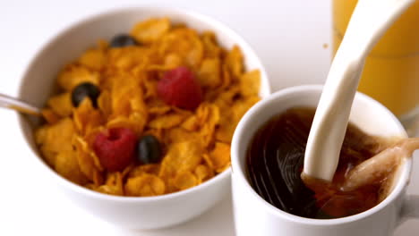 Milk-pouring-into-mug-at-breakfast-table