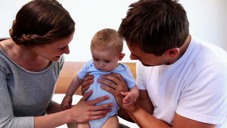 Happy-parents-playing-with-their-baby-son-on-bed