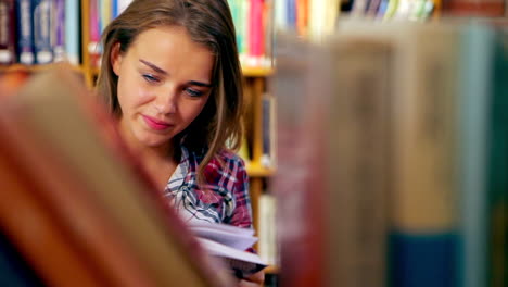 Happy-student-reading-book-standing-in-the-library