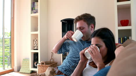 Linda-Pareja-Joven-Relajándose-En-El-Sofá-Con-Café