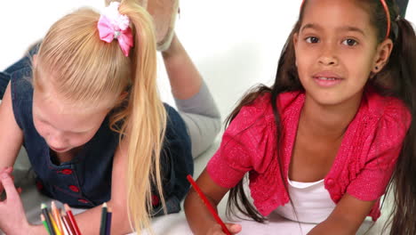 Cute-children-lying-on-floor-drawing-on-paper