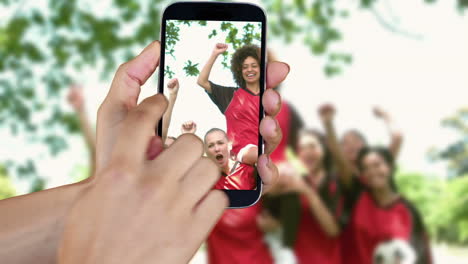 Hand-showing-girls-playing-football-clips-on-smartphone