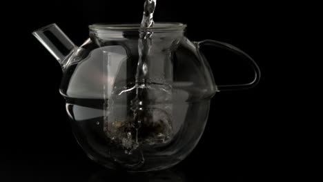 Water-pouring-into-glass-teapot-over-loose-tea
