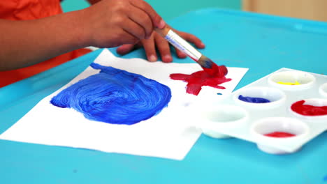 Cute-little-boy-painting-at-table-in-classroom