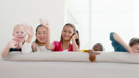 Cute-children-waving-and-smiling-at-camera-on-the-sofa