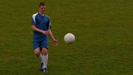 Jugador-De-Fútbol-En-Azul-Pateando-La-Pelota-En-El-Campo