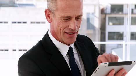 Businessman-using-tablet-pc-and-smiling-at-camera