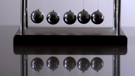 Newtons-cradle-in-motion-on-reflective-surface