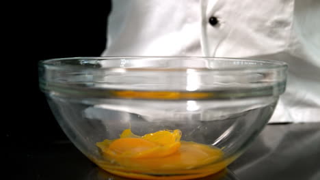 Chef-adding-raw-egg-to-glass-bowl