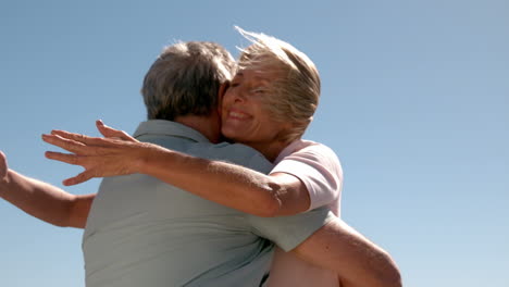 Senior-couple-hugging-on-sunny-day