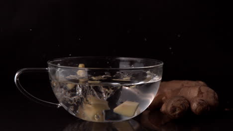 Ginger-slices-falling-into-glass-cup-of-water