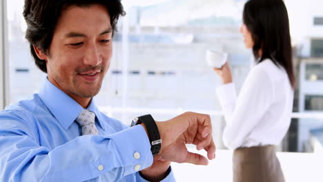 Businessman-using-his-smart-watch-and-smiling