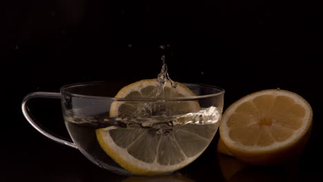 Lemon-slices-falling-into-glass-cup-of-water