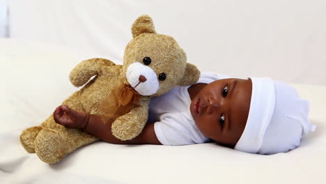 Baby-boy-lying-in-crib-with-teddy-bear