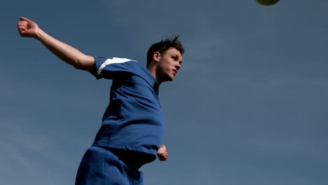 Jugador-De-Fútbol-Dirigiendo-La-Pelota-Bajo-Un-Cielo-Azul