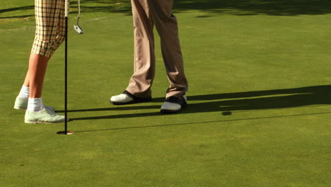Couple-standing-on-the-putting-green-of-golf-course