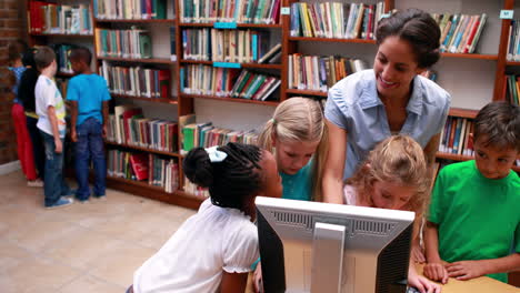Pupils-looking-at-the-computer-in-library-with-their-teacher