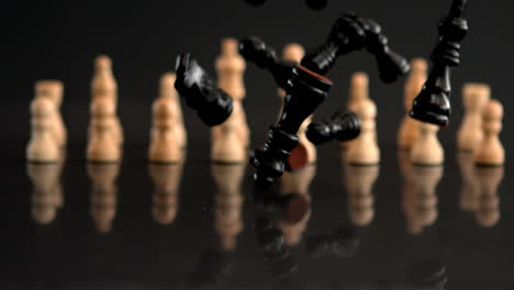 Black-chess-pieces-falling-on-black-background-with-white-pieces