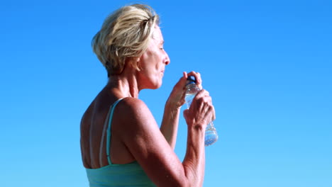 Fit-senior-woman-pausing-on-her-run-to-take-a-drink