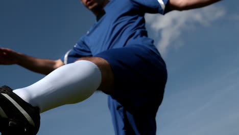 Jugador-De-Fútbol-Pateando-La-Pelota-Bajo-Un-Cielo-Azul