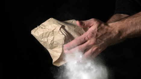 Hand-popping-flour-bag-on-black-background