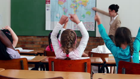 Little-children-listening-to-teacher-showing-the-map-in-classroom-